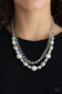 Layers of mismatched silver chains give way to a strand of ornate silver beads and oversized white pearls that cascade below the collar for a refined flair.